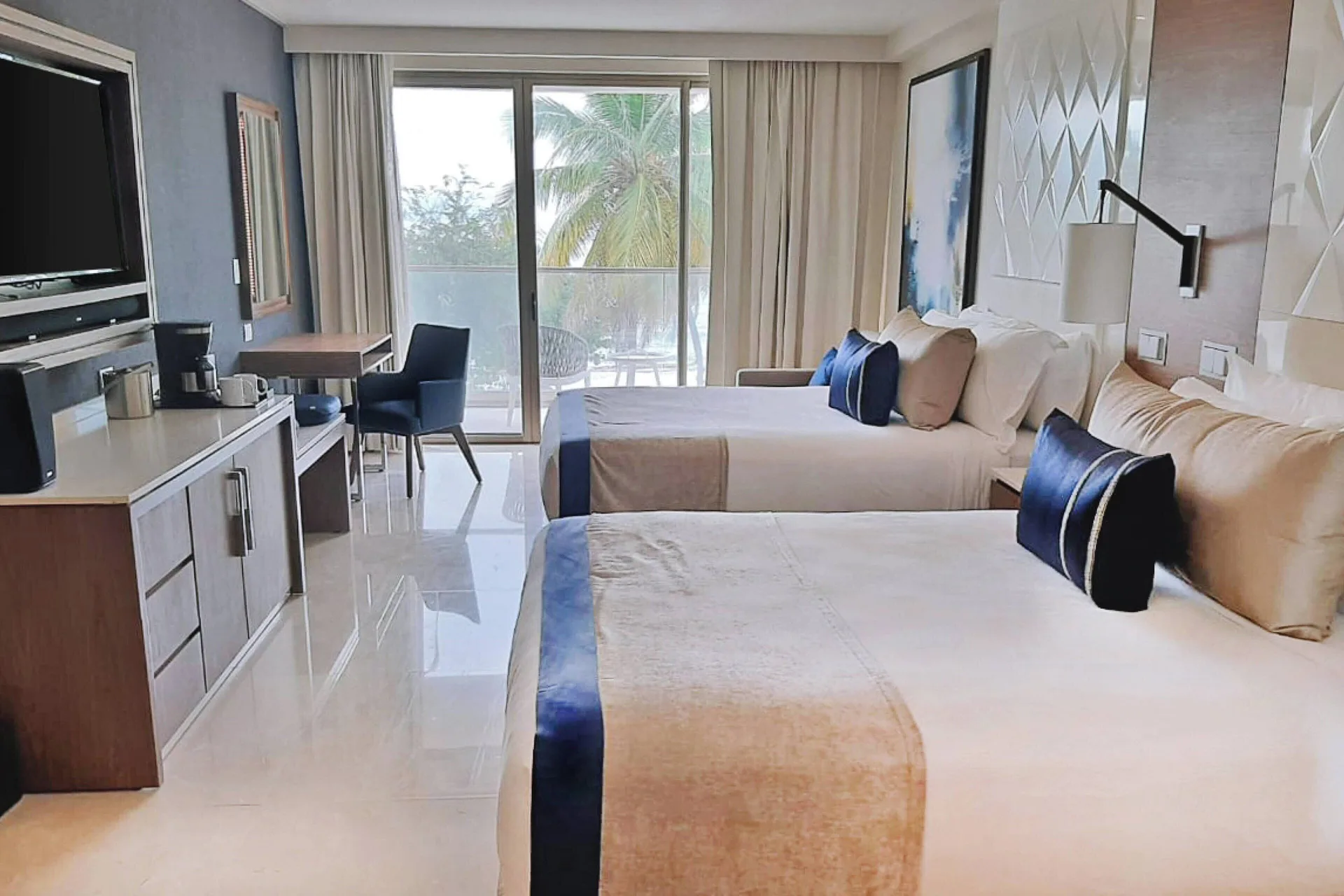 Two-bed suite bedroom with balcony doors and work area at Royalton Grenada.