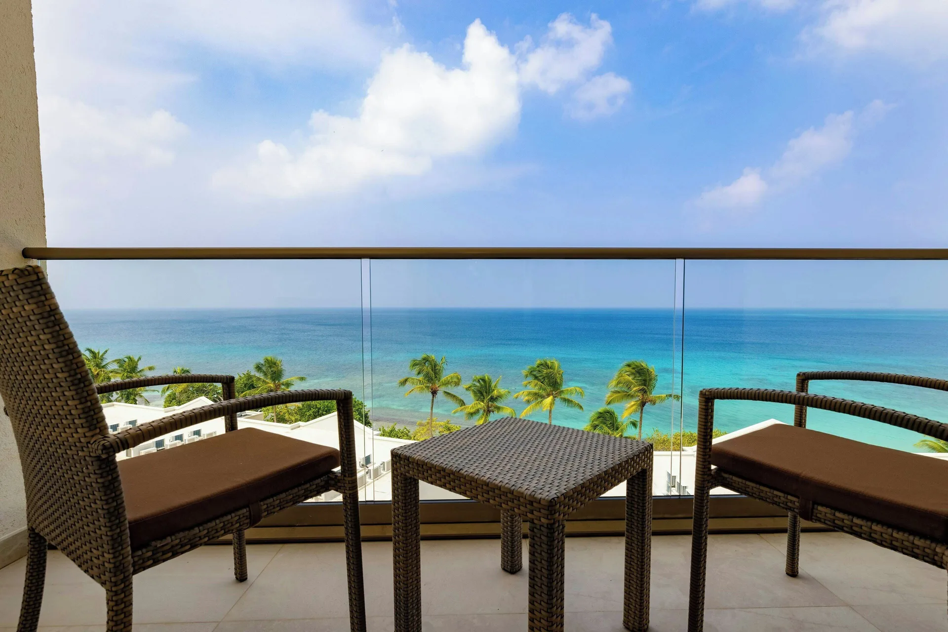 Oceanfront suite balcony with wicker chairs and sea view at Royalton Grenada.