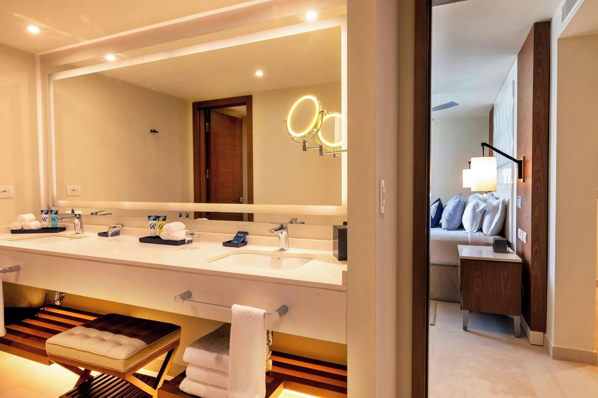 Luxury Room bathroom vanity and bed at Royalton Grenada, with double sinks and a lighted mirror.