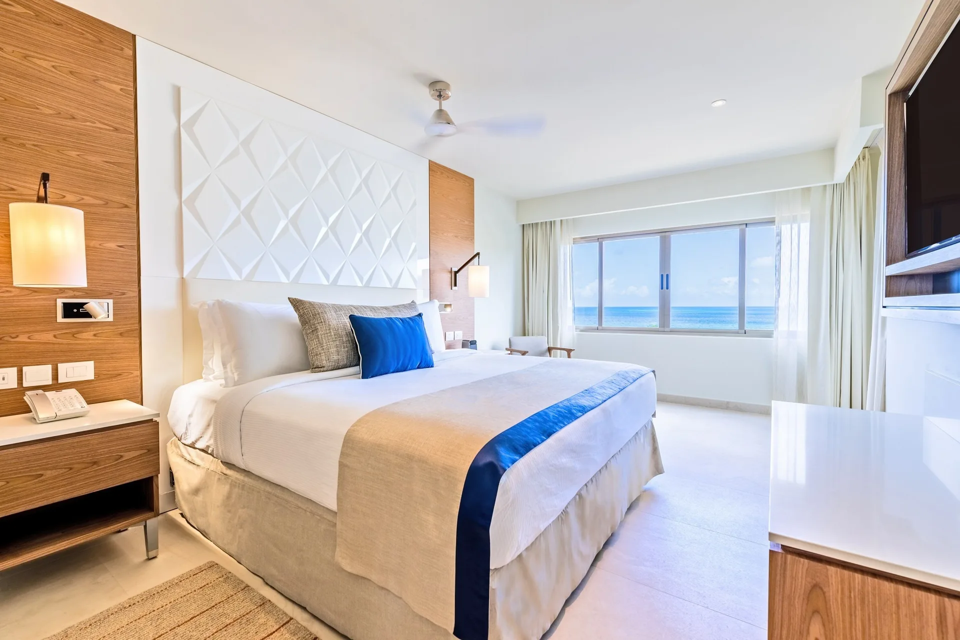 Luxury Room king bed with ocean-view window at Royalton Grenada.