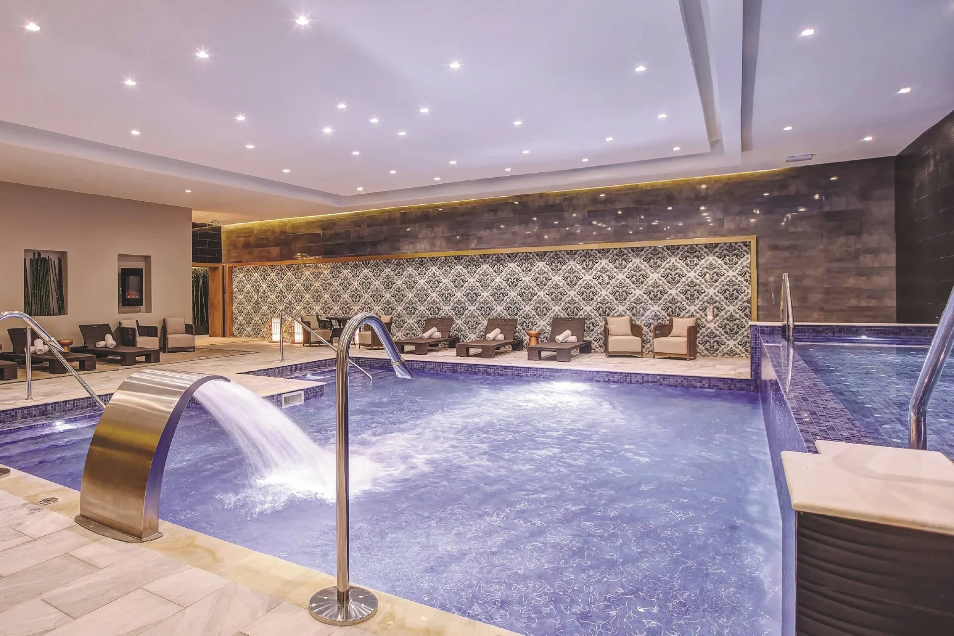 Indoor spa pool with water feature and lounge seating at Royalton Negril.