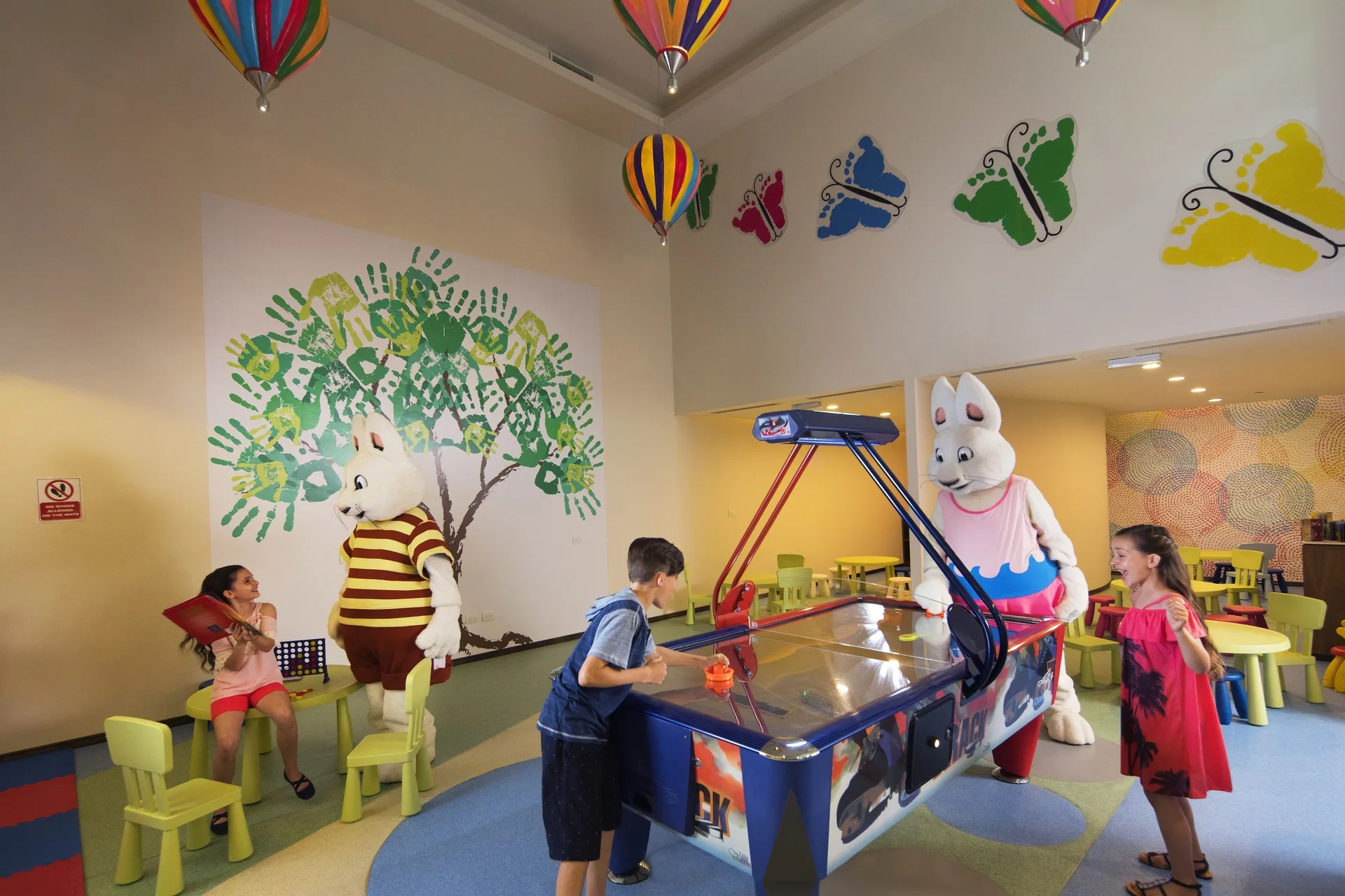 Children play air hockey in a colorful kids club room at Royalton Negril.