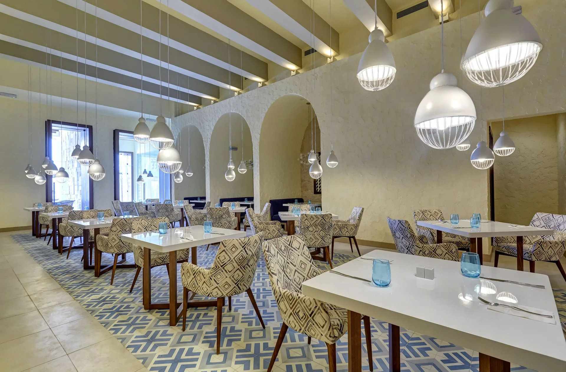 Airy dining room with white tables and patterned chairs at Royalton Negril.