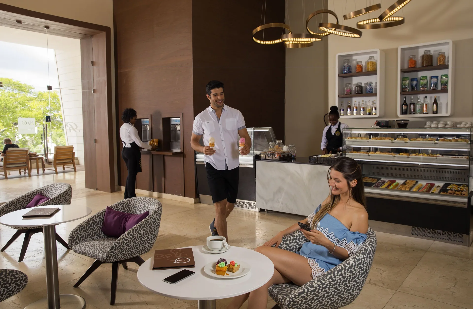 Cafe lounge with display cases, seating, and guests at Royalton Negril.
