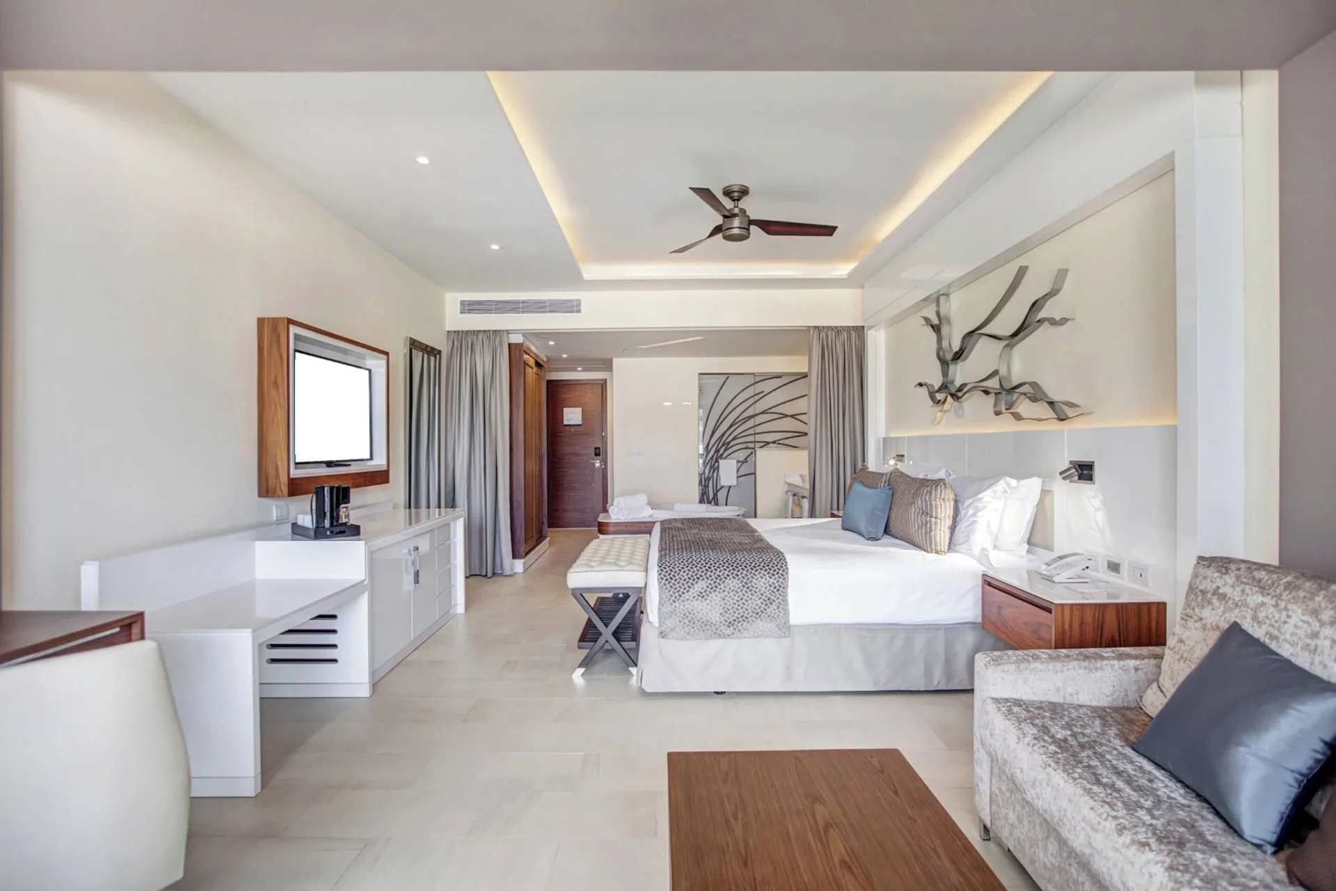 Luxury Junior Suite king bed, sofa, desk, and TV at Royalton Negril.
