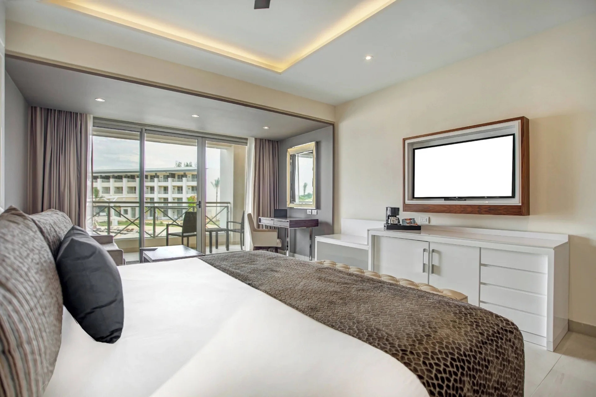 Luxury Junior Suite king bed facing TV and balcony at Royalton Negril.