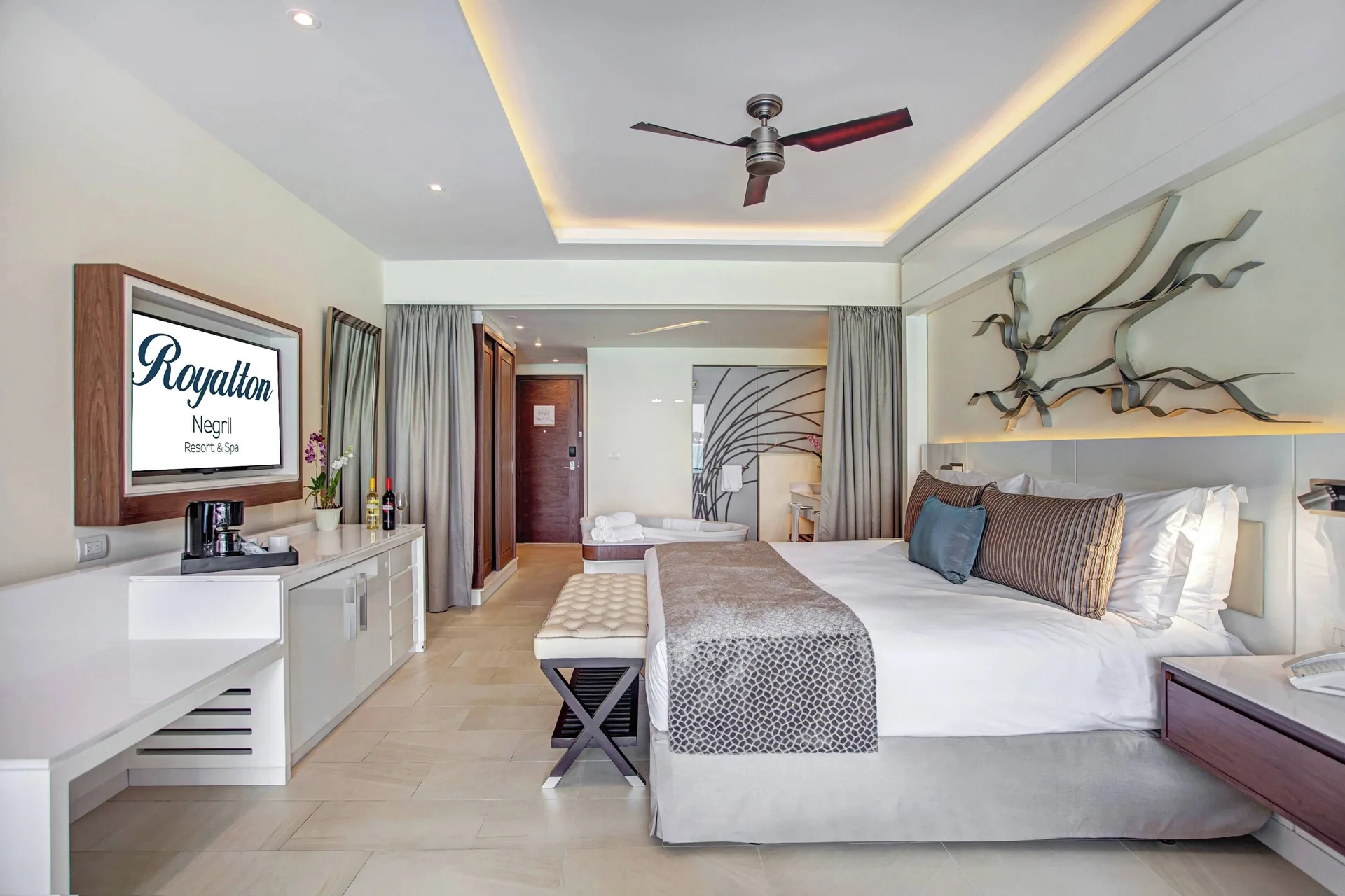 Luxury Junior Suite king bed with TV and branded screen at Royalton Negril.