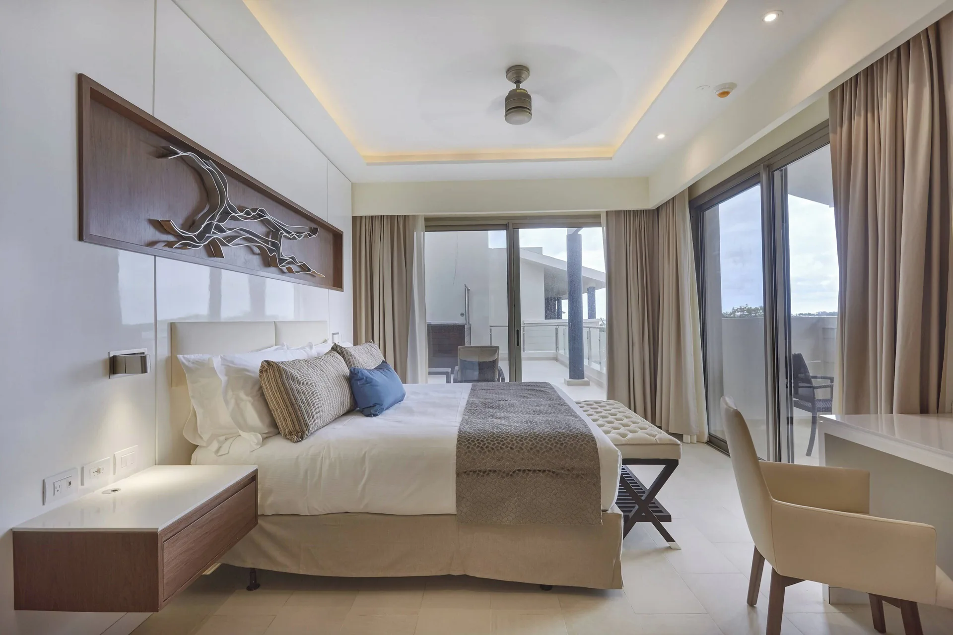 King bedroom with wall art, desk chair and terrace doors at Royalton Negril.