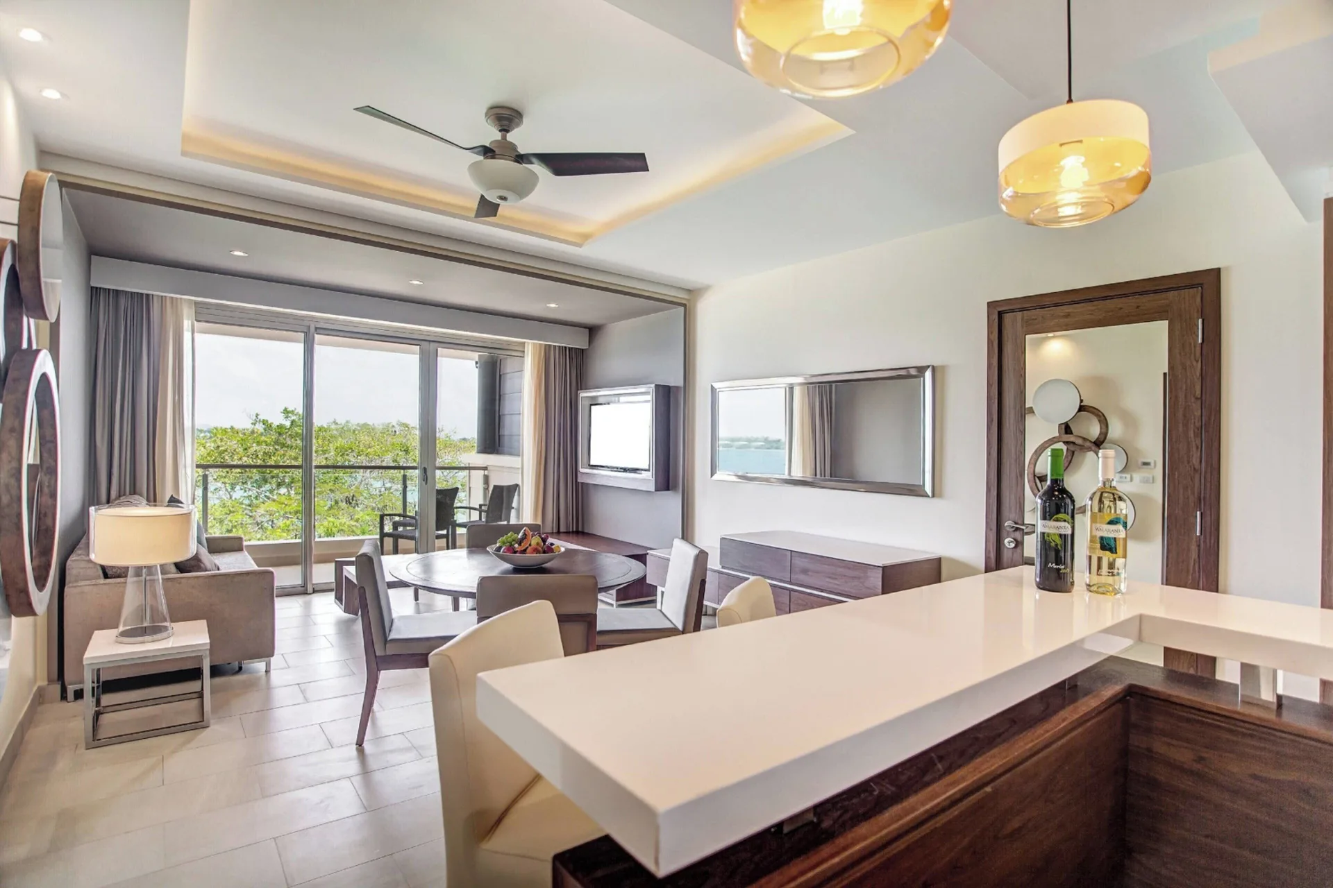 Ocean-view presidential suite living and dining area at Royalton Negril with balcony doors and kitchenette.