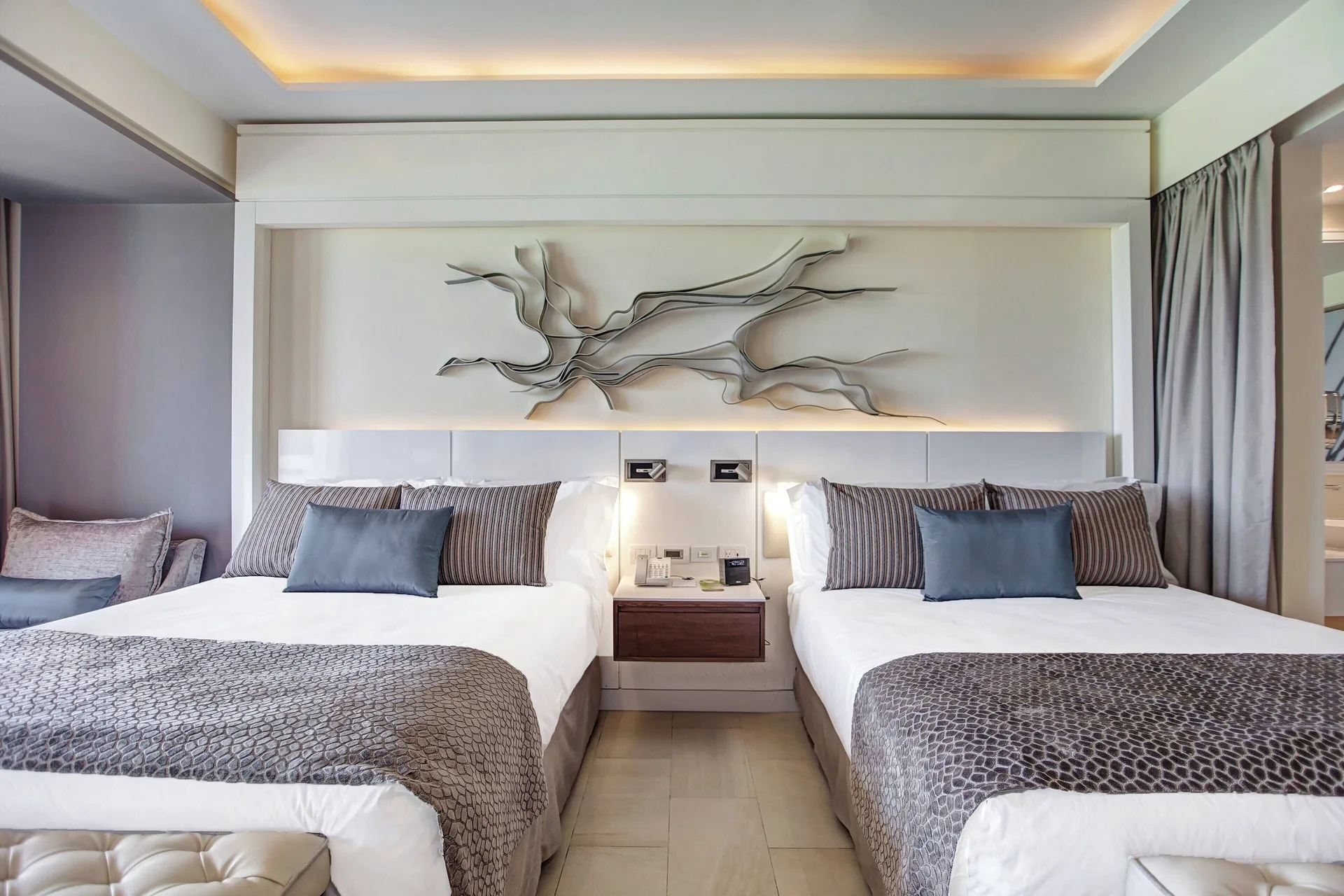 Two beds with patterned throws and wall art in a Royalton Negril ocean view suite bedroom.