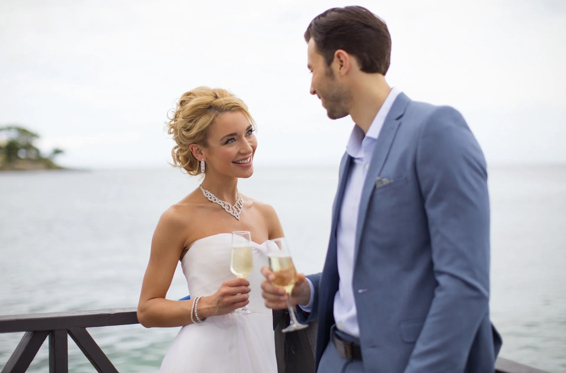 Bride and groom toast with champagne by the water at Royalton Negril.