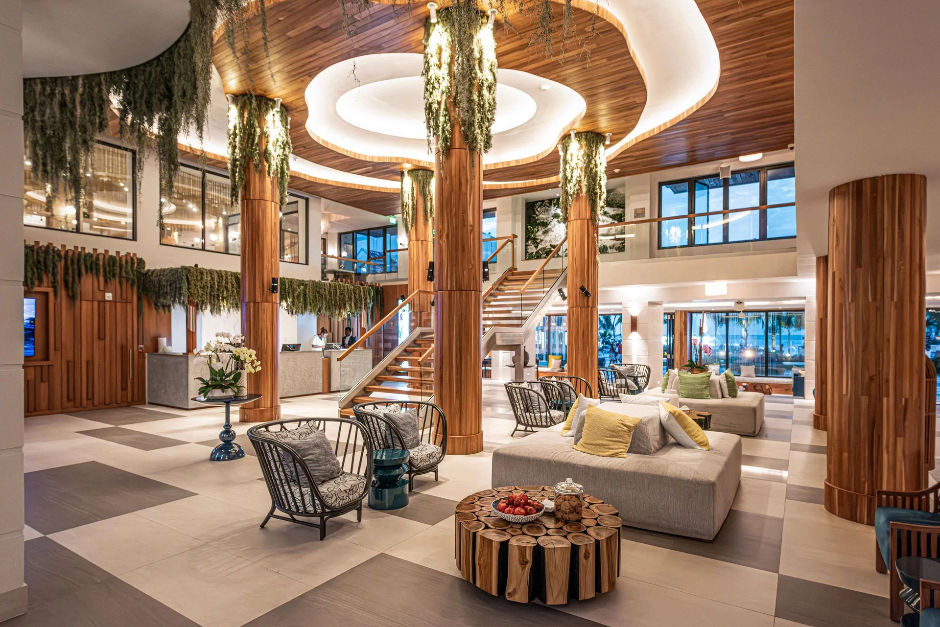 Evening lobby view with staircase, reception desks, seating, and illuminated columns at Sandals Dunns River.