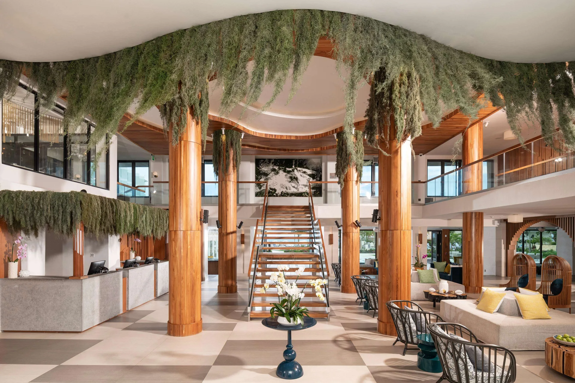 Grand lobby with staircase, wood columns, hanging greenery, and seating at Sandals Dunns River.