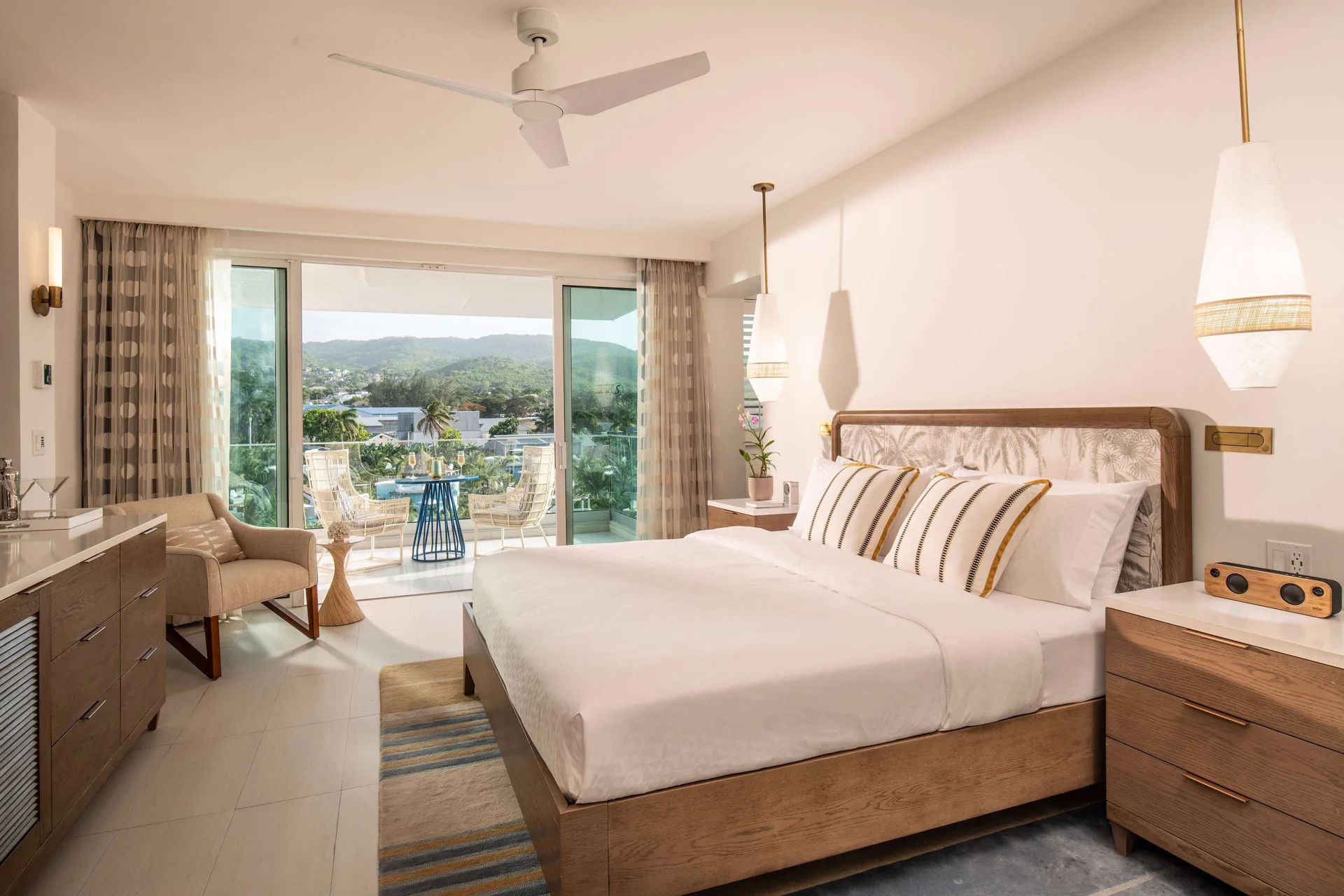 Guest room with king bed, balcony seating, and mountain view at Sandals Dunns River.