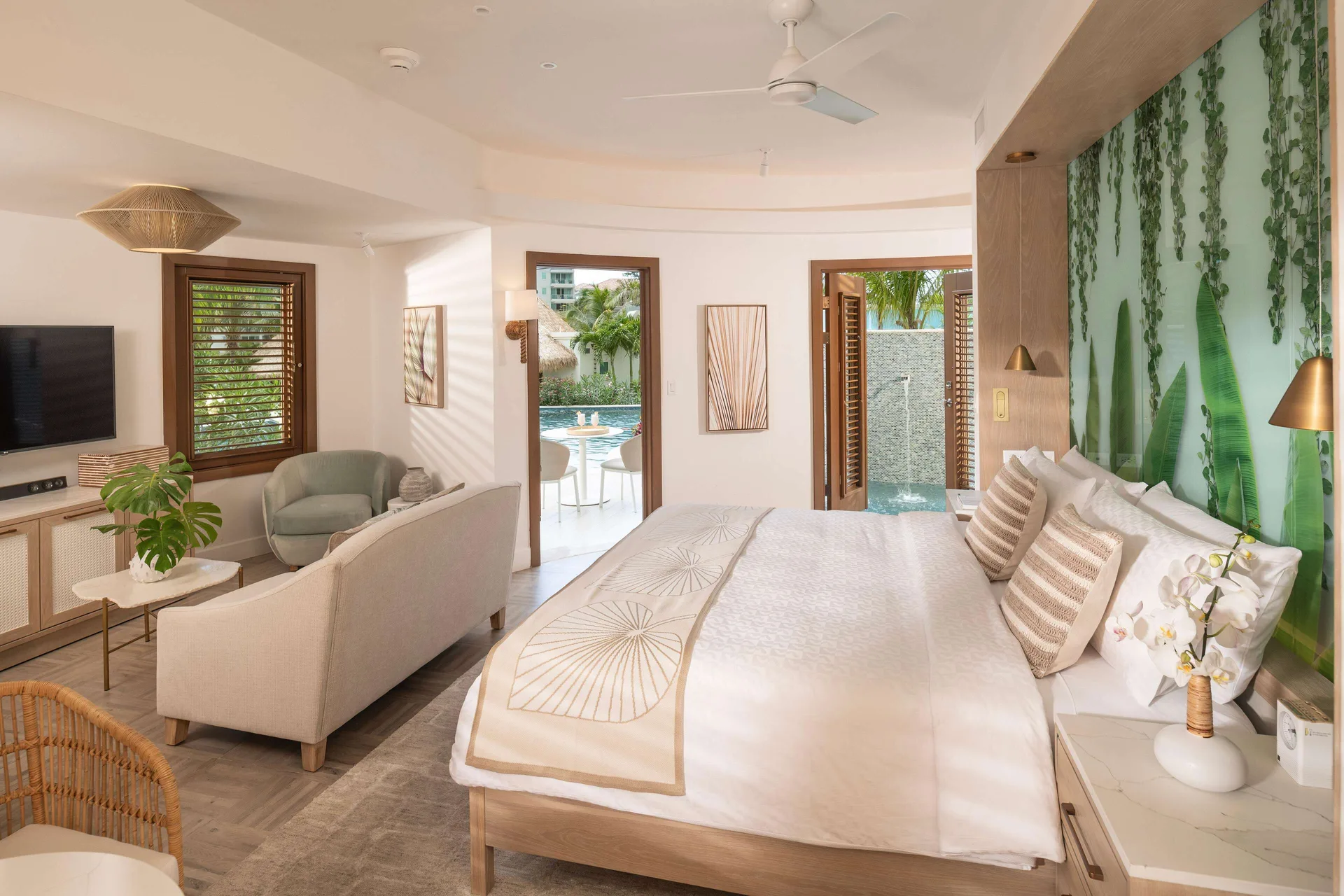 Guest room with king bed, sitting area, plant mural, and outdoor soaking tub at Sandals Dunns River.