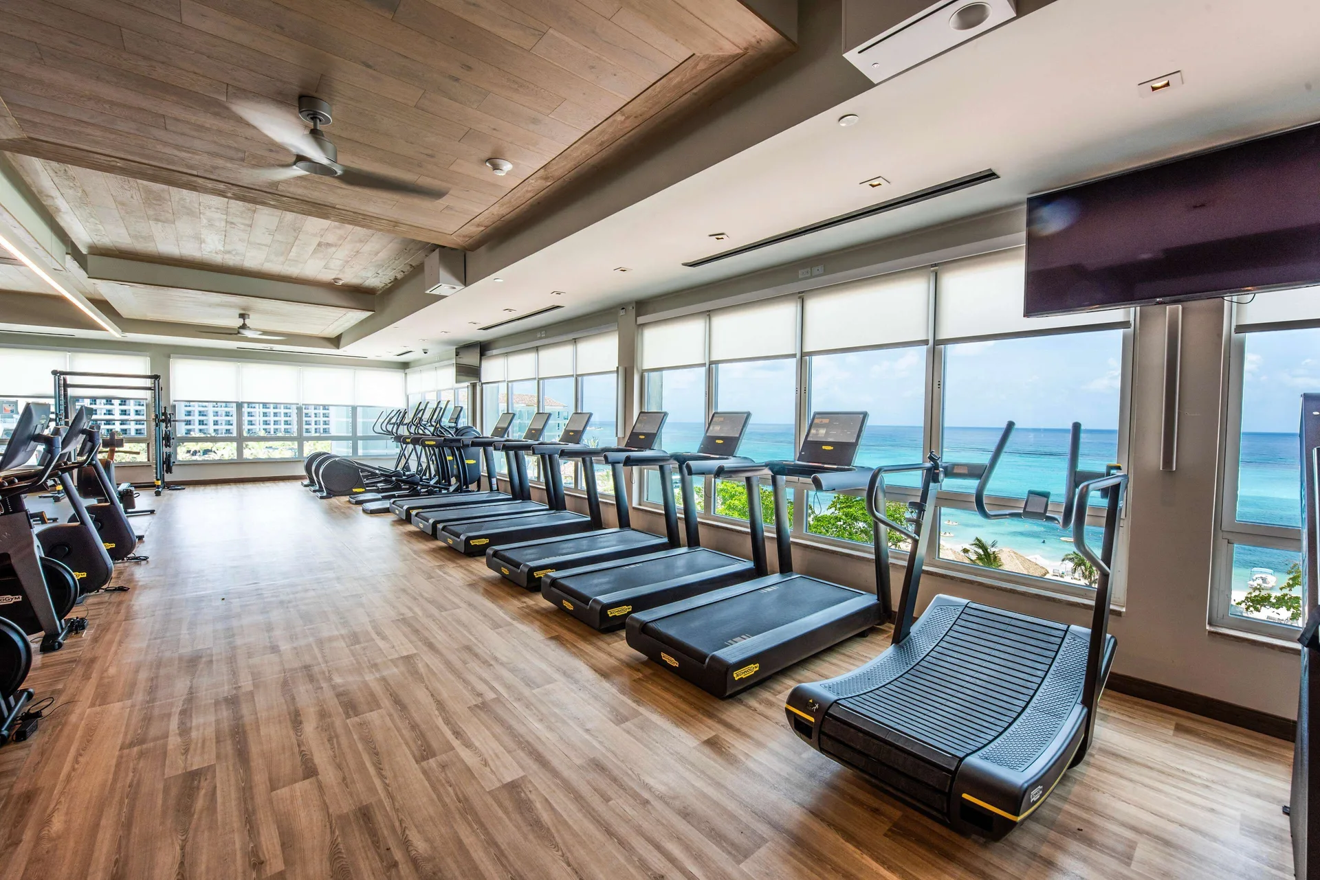 Ocean-view fitness room with rows of treadmills at Sandals Dunns River.