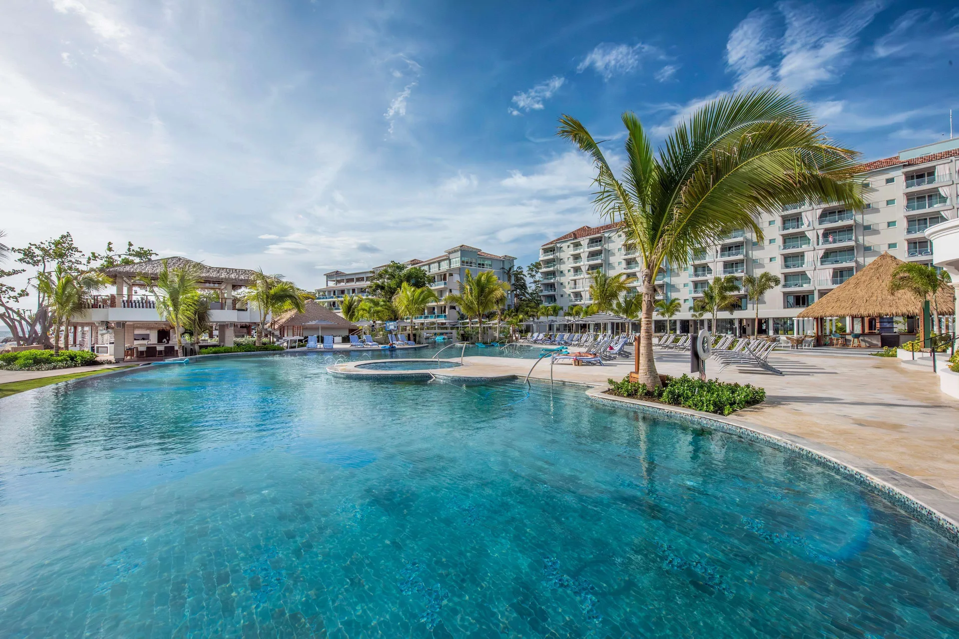 Resort pool with palms and guest buildings at Sandals Dunns River.