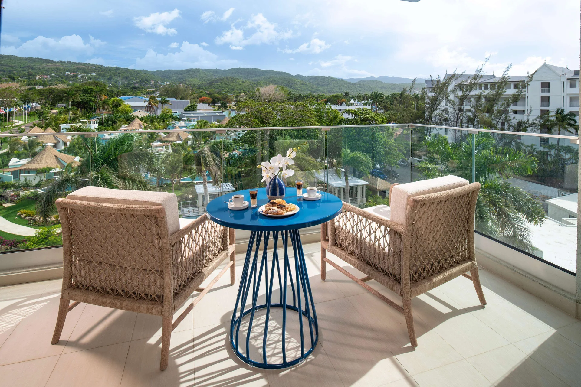 Luxury Room balcony seating with garden and hillside view at Sandals Dunns River.