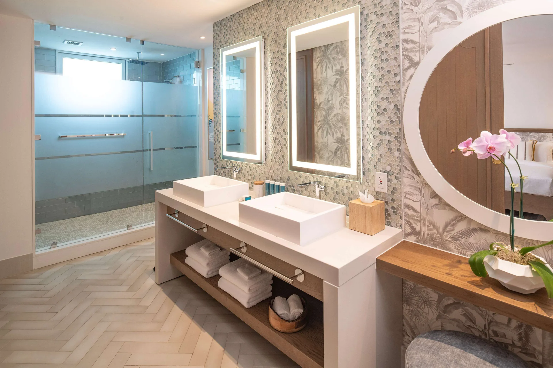 Bathroom with double vanity and glass shower in a beachfront club room at Sandals Dunns River.