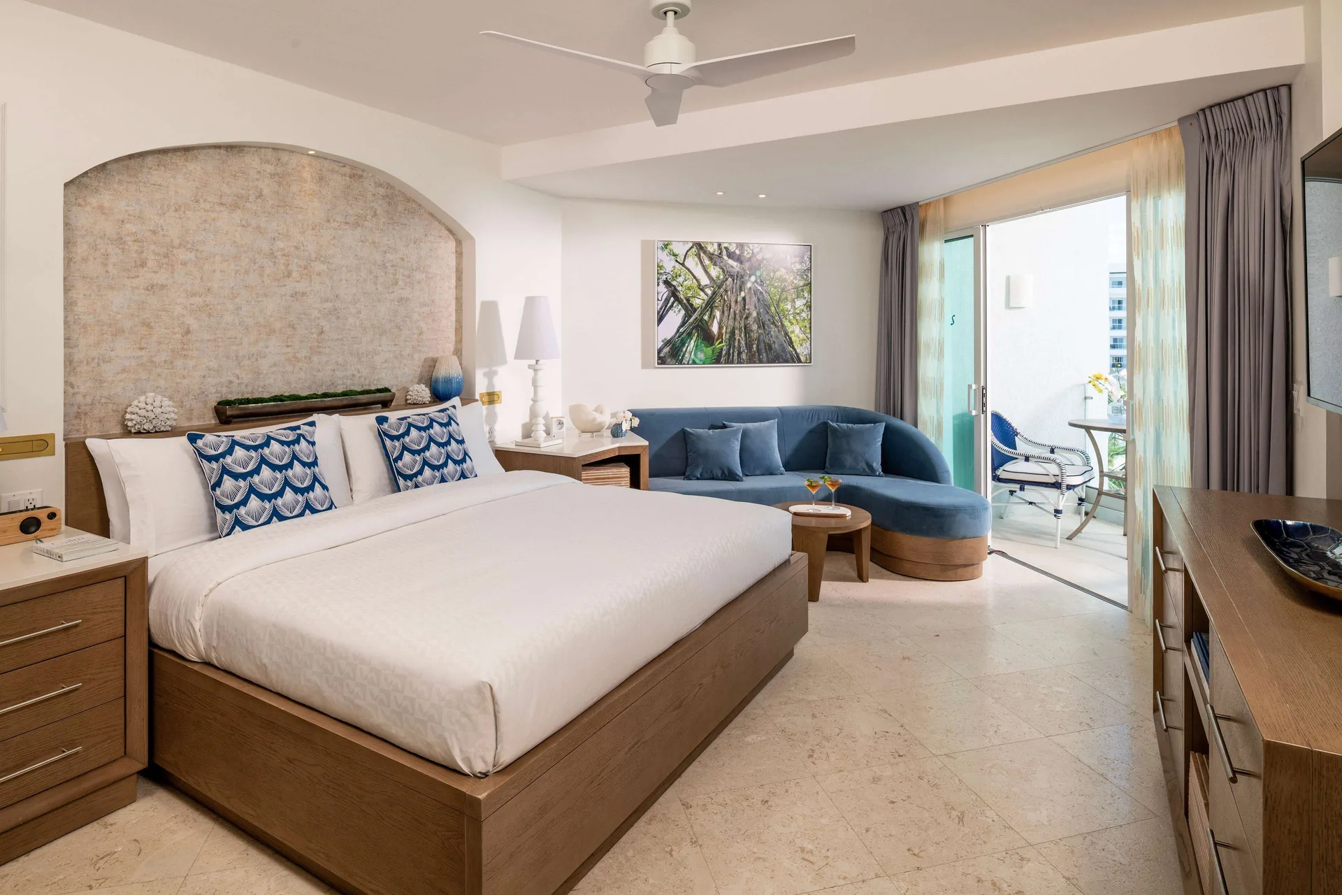 Mammee Bay Club Level balcony room with king bed and blue sofa at Sandals Dunns River.
