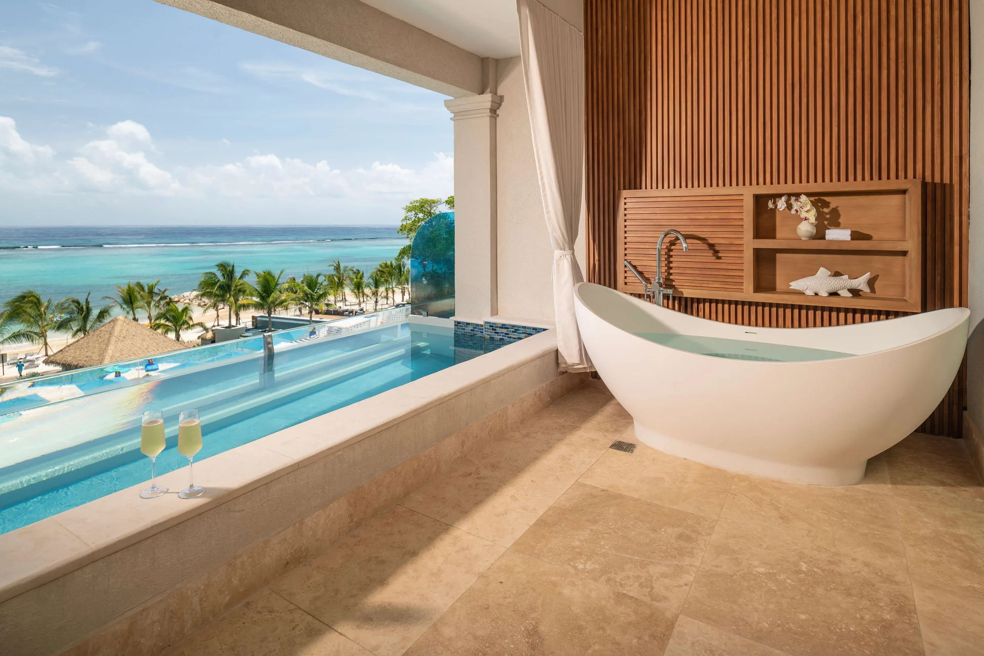 Ocean-view balcony with skypool and white soaking tub at Sandals Dunns River.