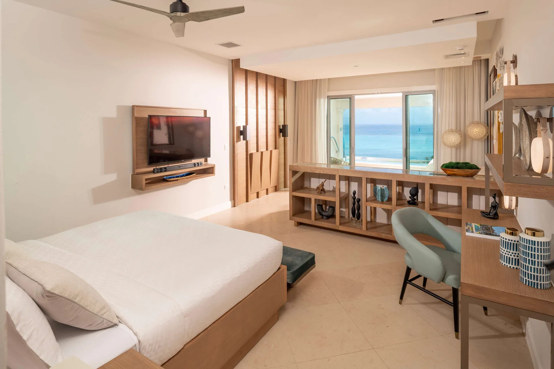 King bed, desk, TV, and ocean-facing balcony doors at Sandals Dunns River.