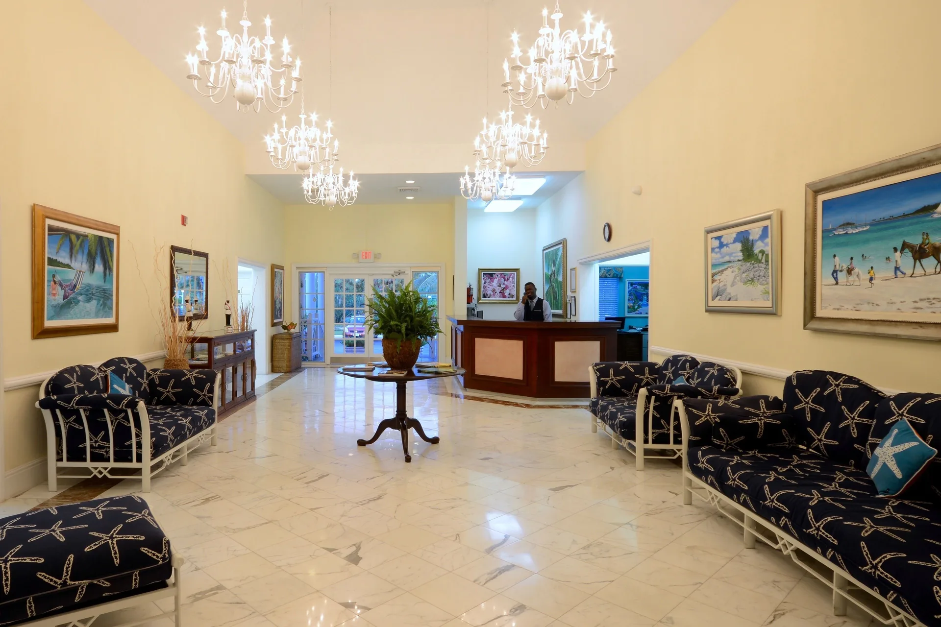 The lobby at Sandyport Beach Resort has chandeliers, seating, artwork, and a front desk.
