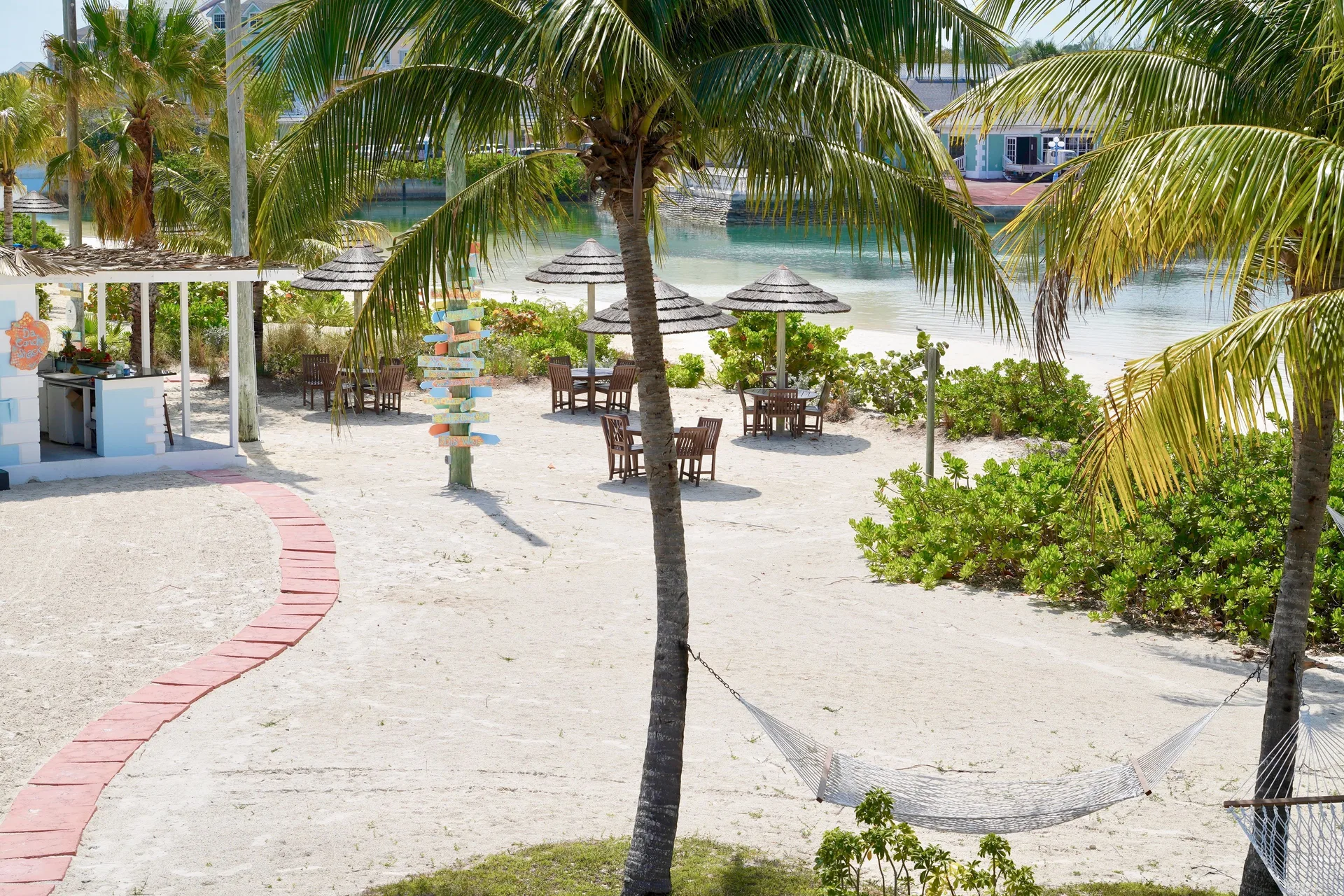 Sandy courtyard with hammocks, palms and shaded tables at Sandyport Beach Resort.