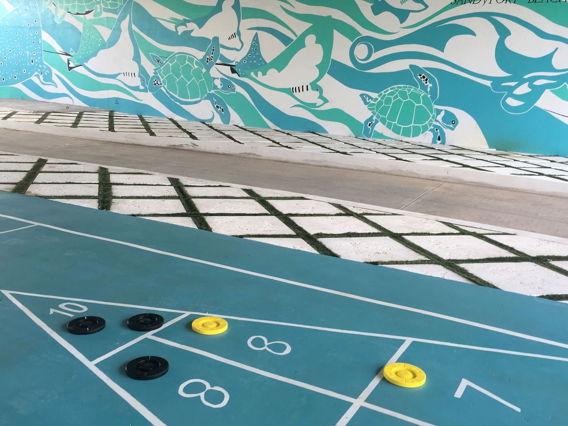 Shuffleboard court with discs and sea-life mural at Sandyport Beach Resort.