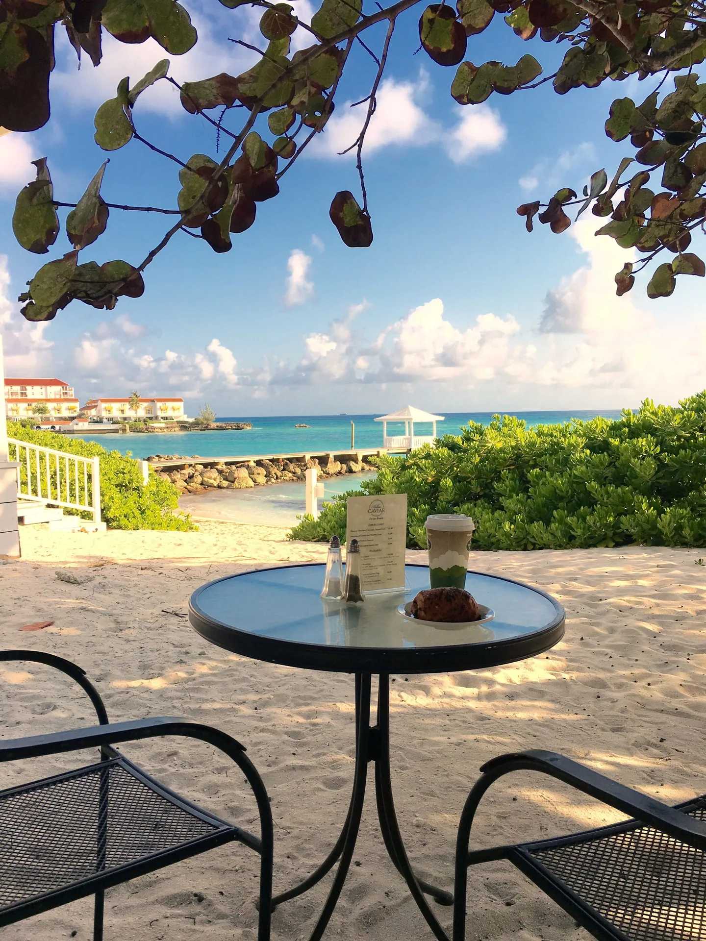 Beach café table with pastry and drink facing the water at Sandyport Beach Resort.