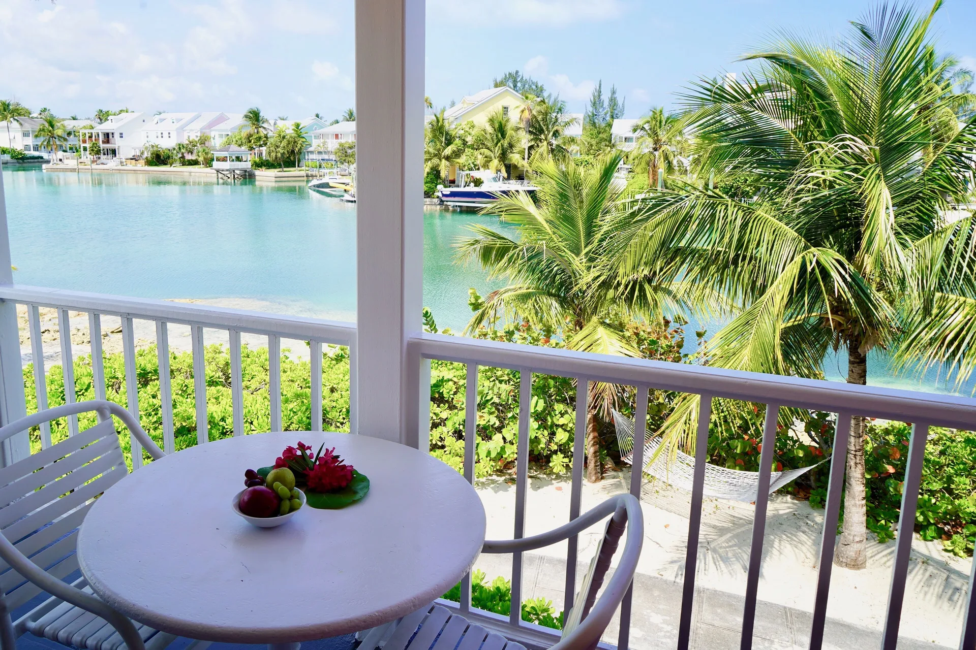 Deluxe suite balcony table with palm and canal views at Sandyport Beach Resort.