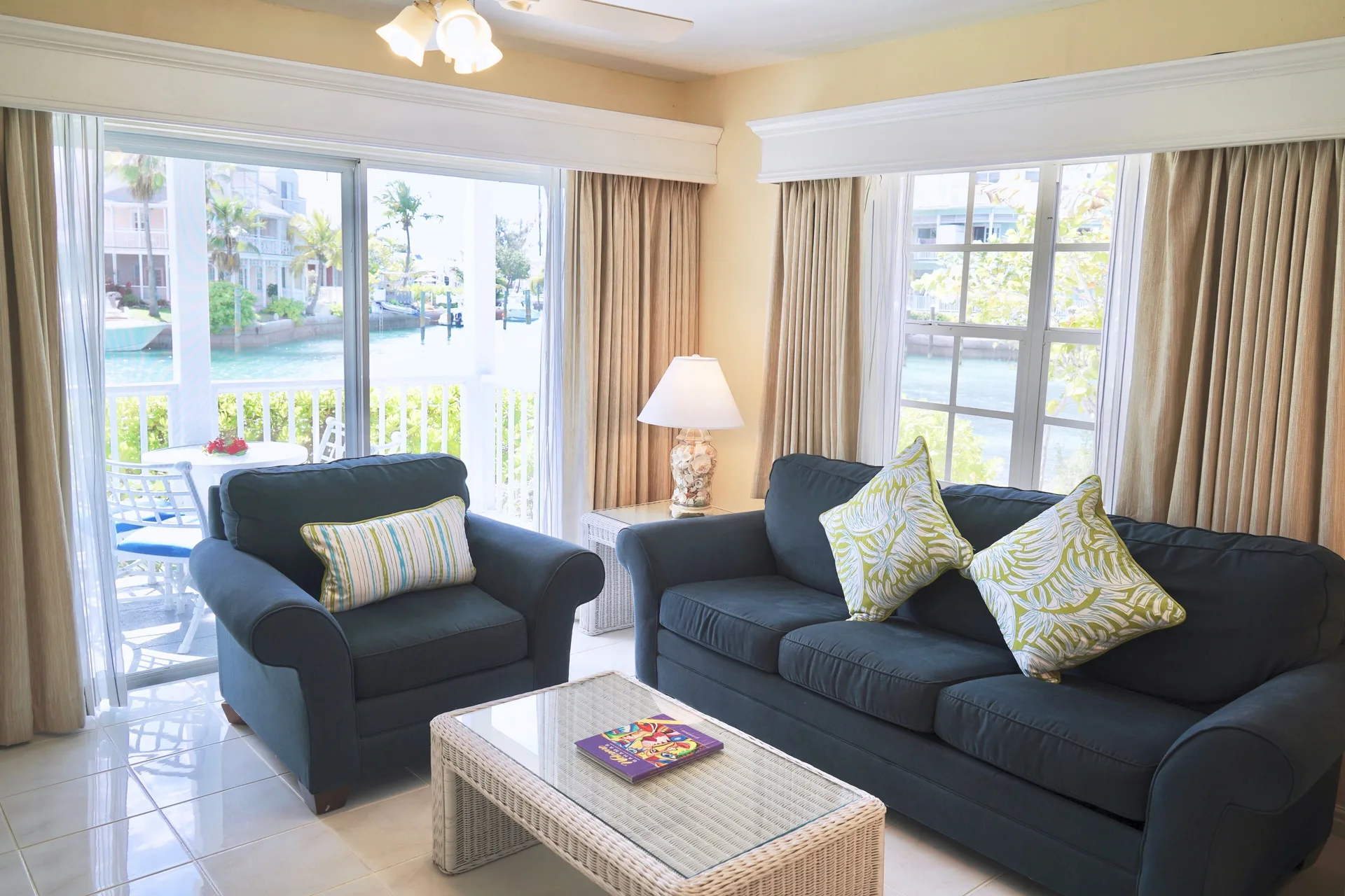 Deluxe suite lounge with blue sofabed and balcony view at Sandyport Beach Resort.