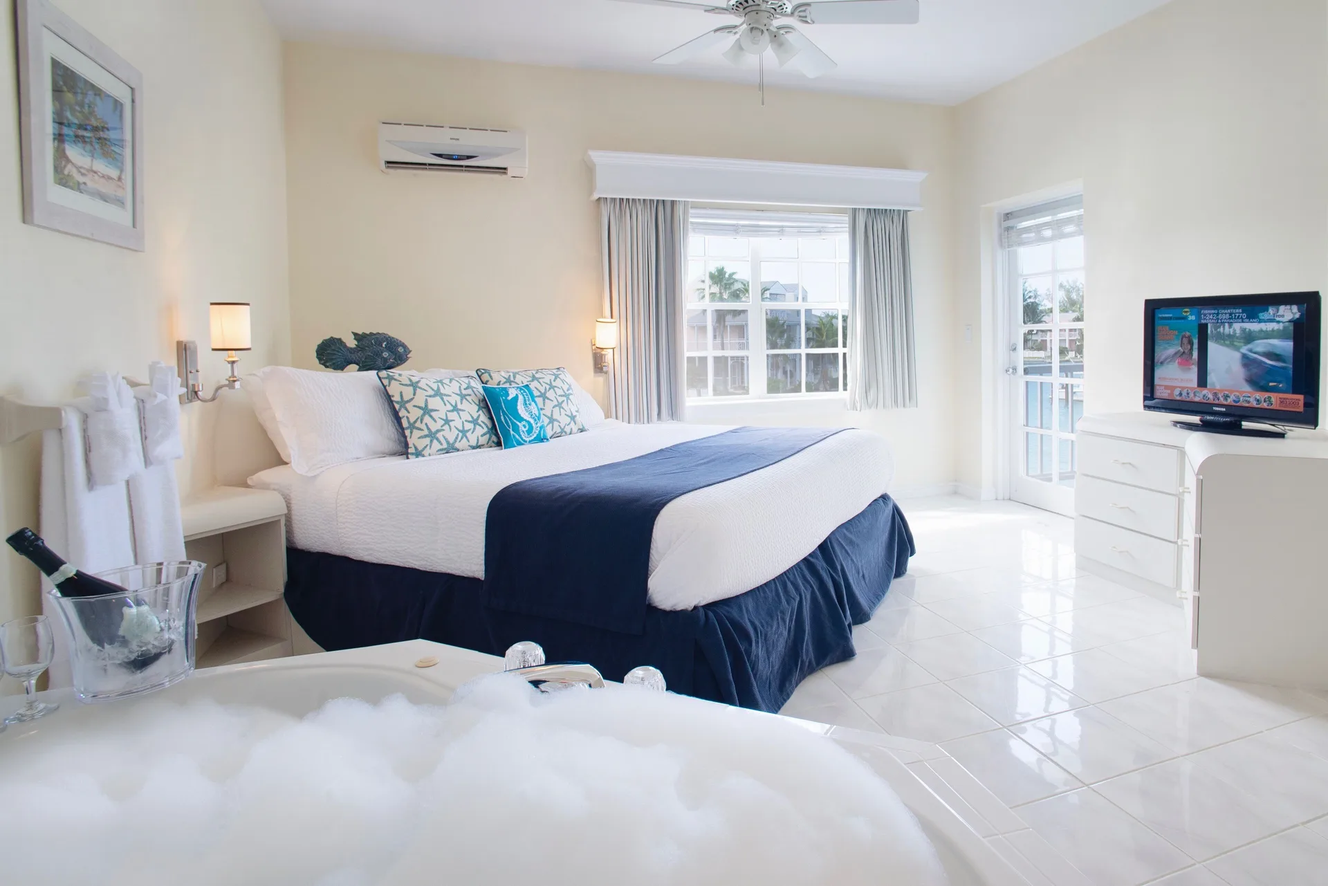 Deluxe suite bedroom with king bed and jetted tub at Sandyport Beach Resort.