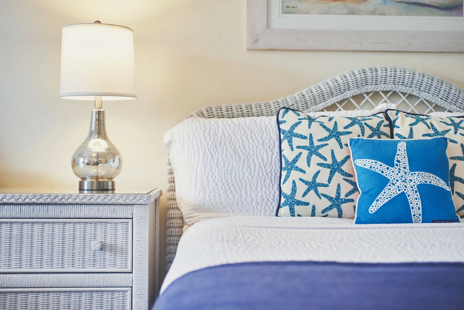 Standard Room bed with wicker headboard and starfish pillows at Sandyport Beach Resort.