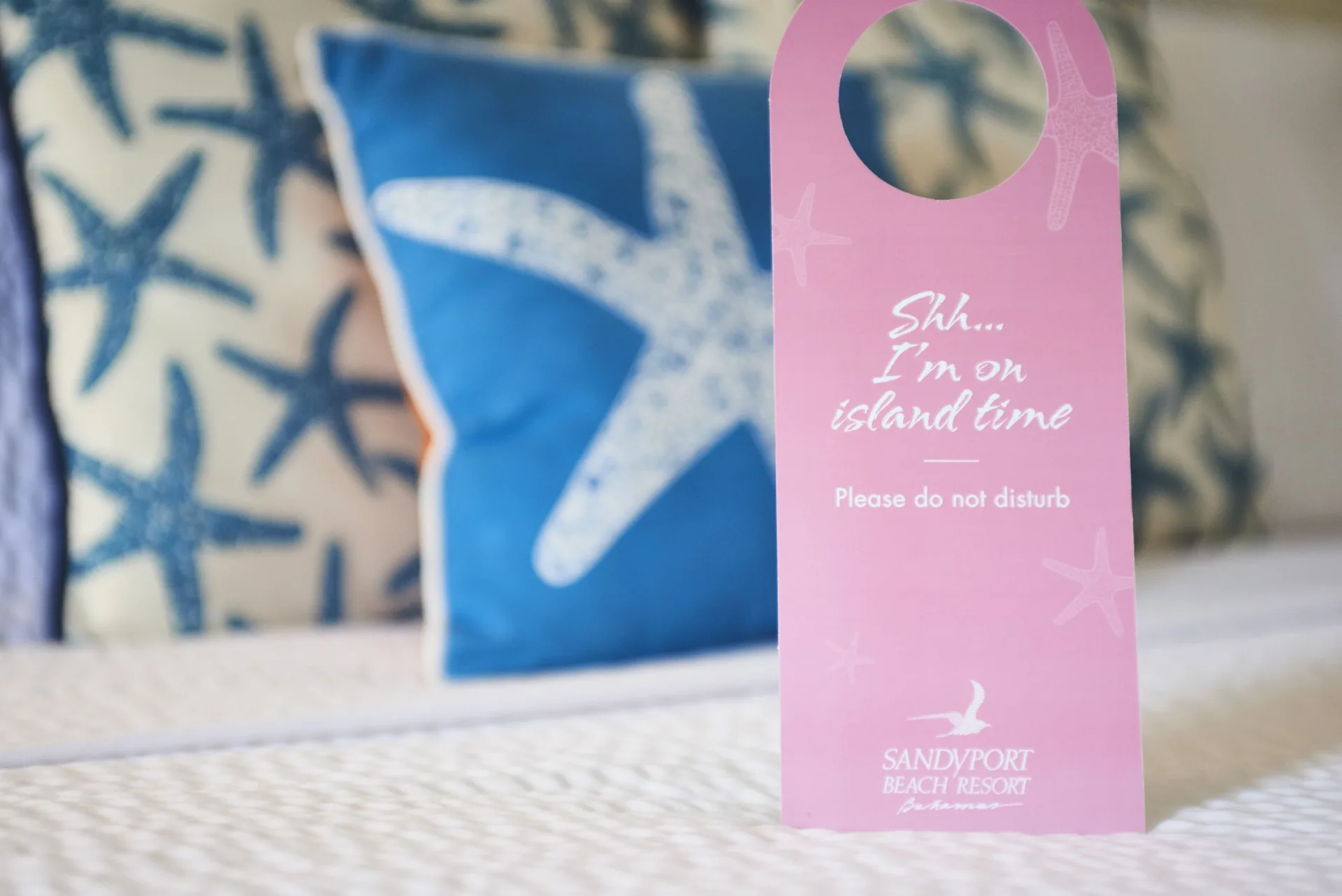 Standard Room bed with a pink do-not-disturb sign at Sandyport Beach Resort.