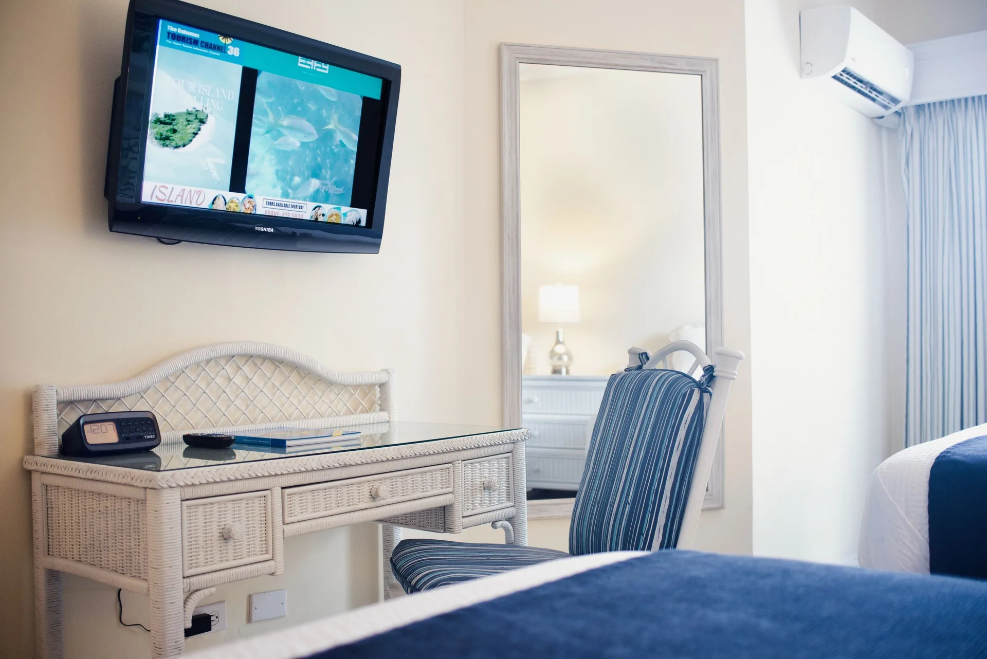 Standard Room desk, wall TV, mirror, and bed edge at Sandyport Beach Resort.