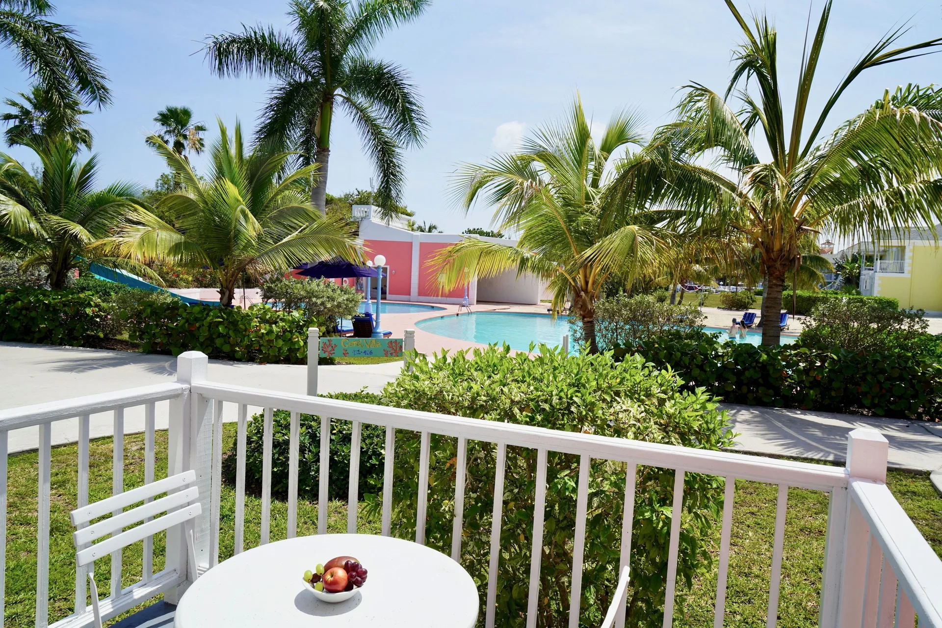 Studio suite balcony overlooking pool and palm trees at Sandyport Beach Resort.