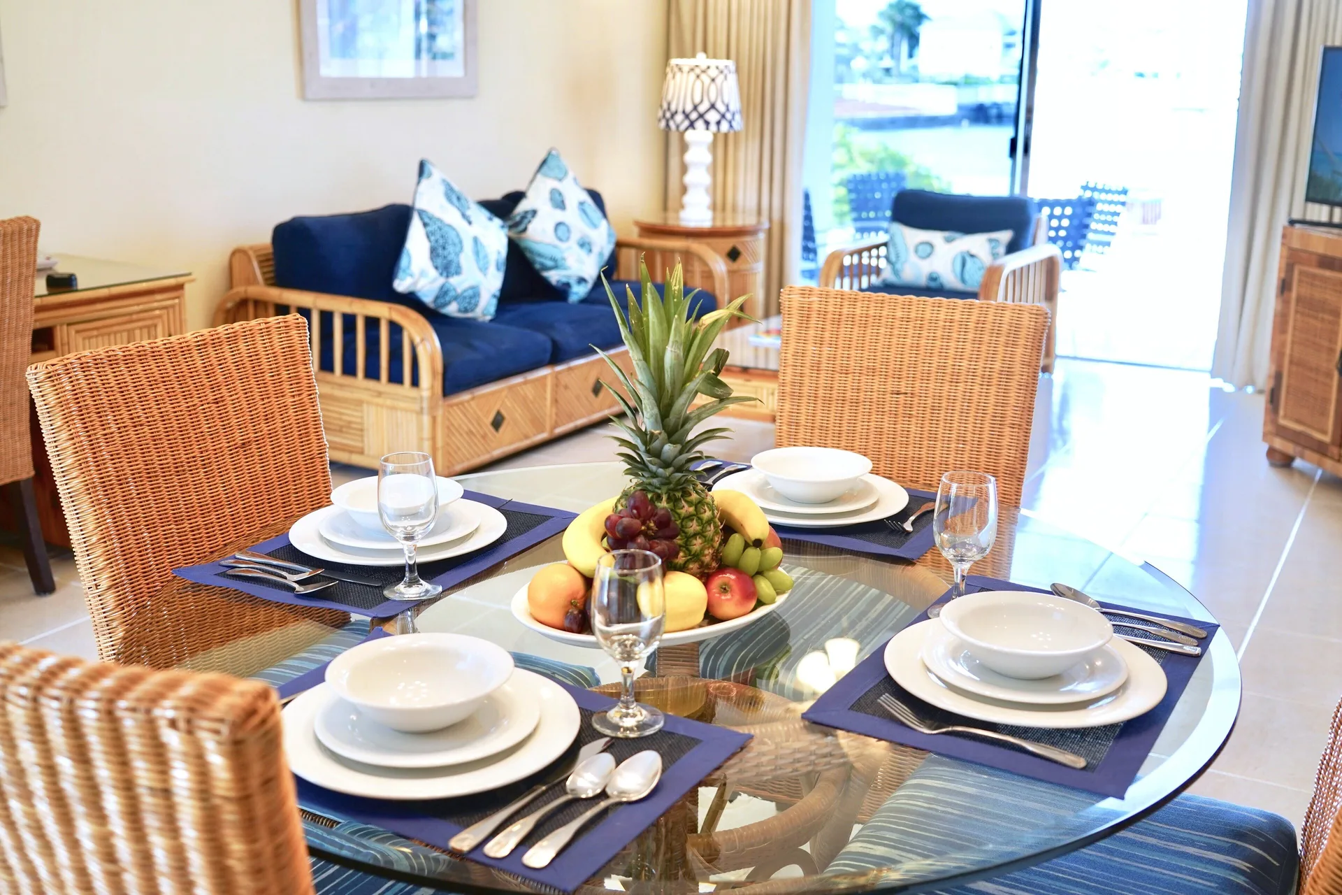 Dining table, fruit bowl, and blue sofa seating in a suite at Sandyport Beach Resort.