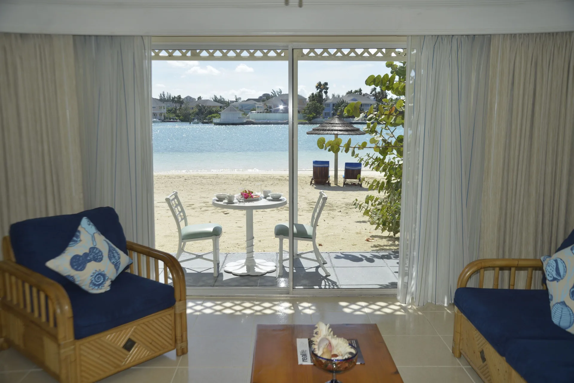 Living room seating opens to a sandy lagoon patio at Sandyport Beach Resort.