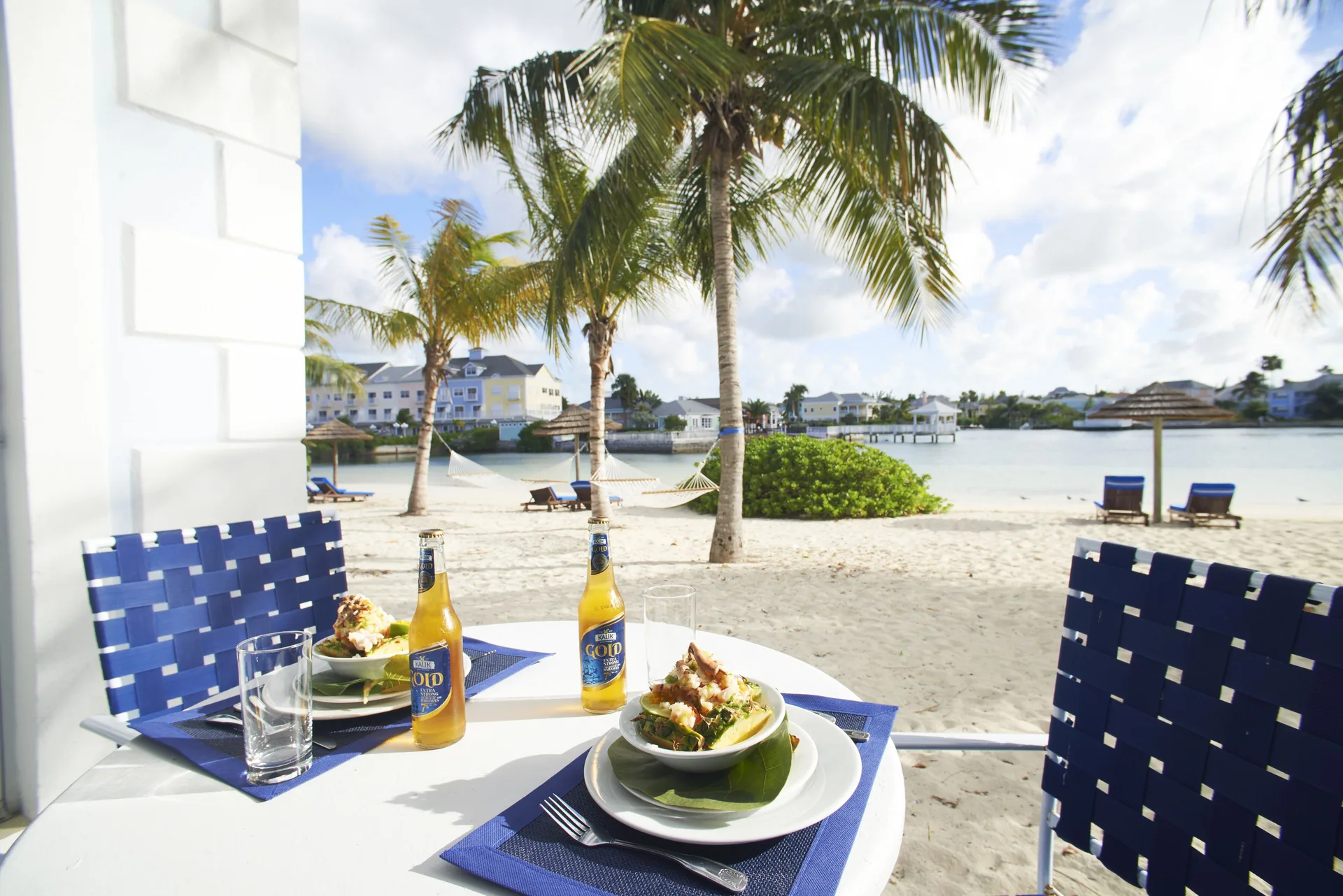 Patio table with meals and drinks facing the sandy lagoon at Sandyport Beach Resort.