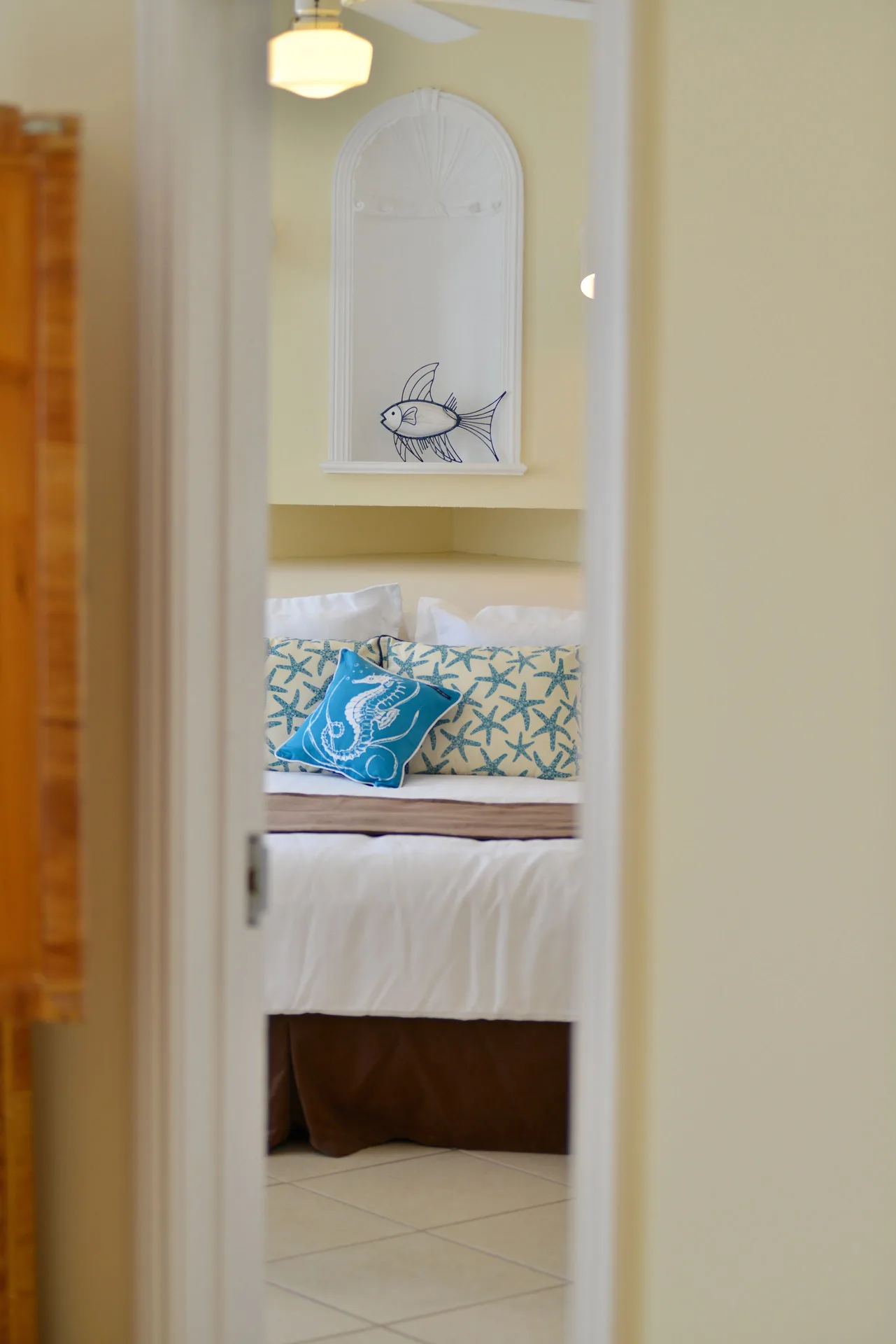 Bedroom doorway view of a white bed with coastal pillows at Sandyport Beach Resort.
