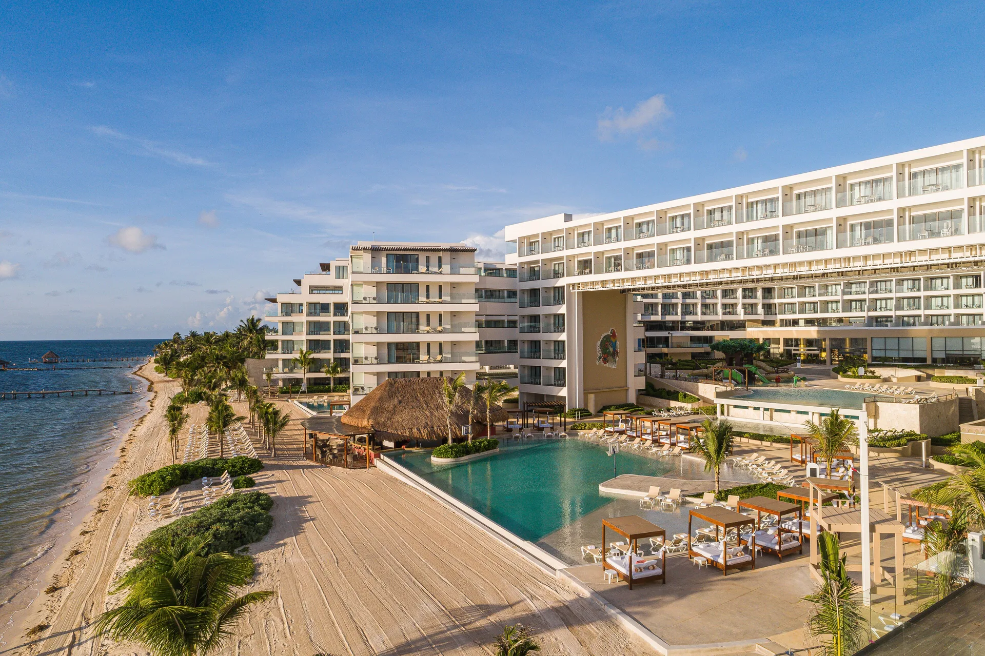 Beachfront resort buildings, pool, and shoreline at Sensira Resort & Spa Riviera Maya.