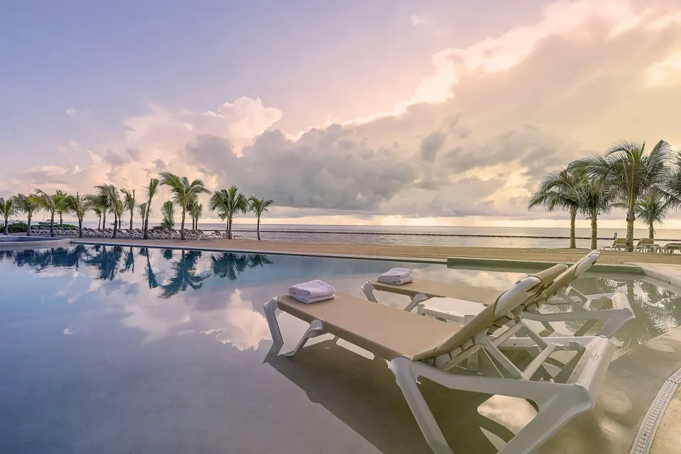 Partially submerged loungers by the pool and beach at Sensira Resort & Spa Riviera Maya.