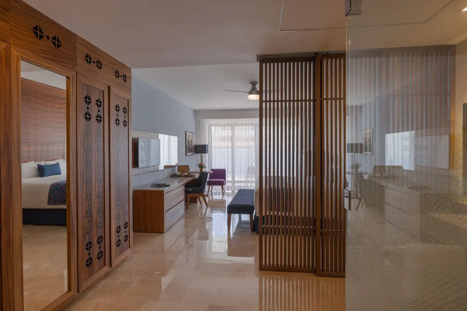 Agatha room entry with wardrobe, glass shower, and bedroom beyond at Sensira Resort & Spa Riviera Maya.