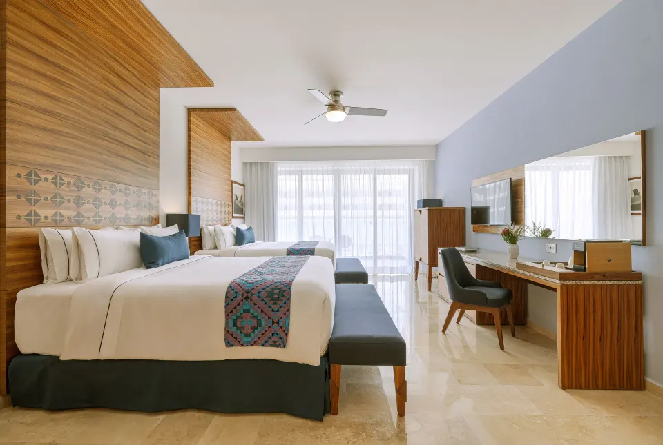 Agatha room with two beds, benches, and desk at Sensira Resort & Spa Riviera Maya.