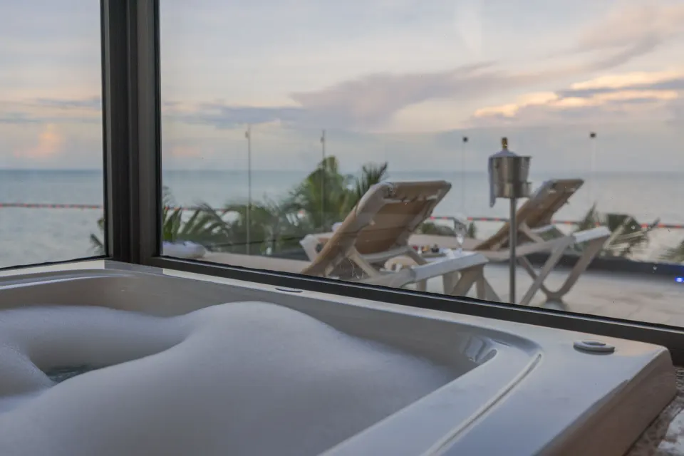 Ruby Suite hot tub beside windows facing terrace loungers and sea at Sensira Resort & Spa Riviera Maya.