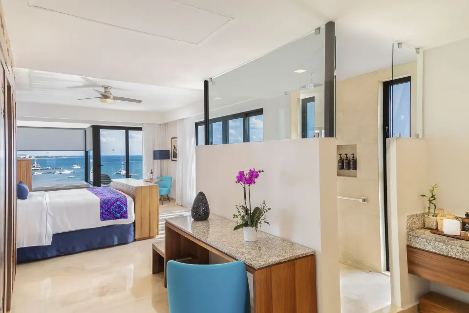 Ruby Suite bedroom, desk, bath area, and ocean view at Sensira Resort & Spa Riviera Maya.