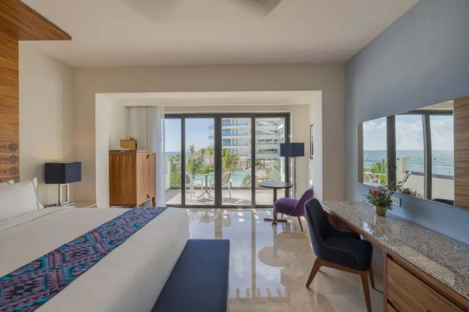 Sapphire Room bed, desk, balcony, and ocean view at Sensira Resort & Spa Riviera Maya.