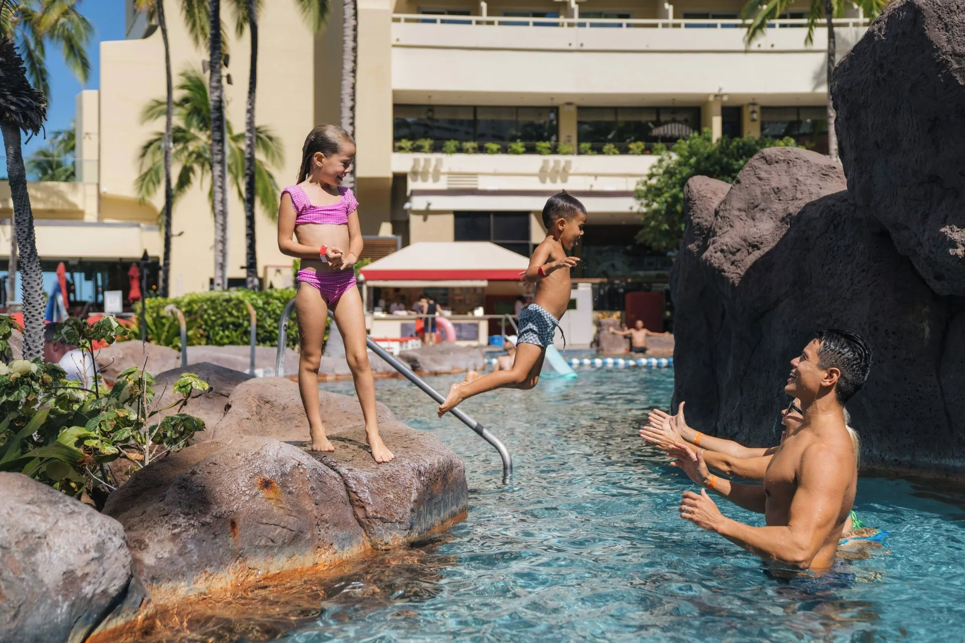 Children playing with an adult in the resort pool at Sheraton Waikiki Beach Resort.
