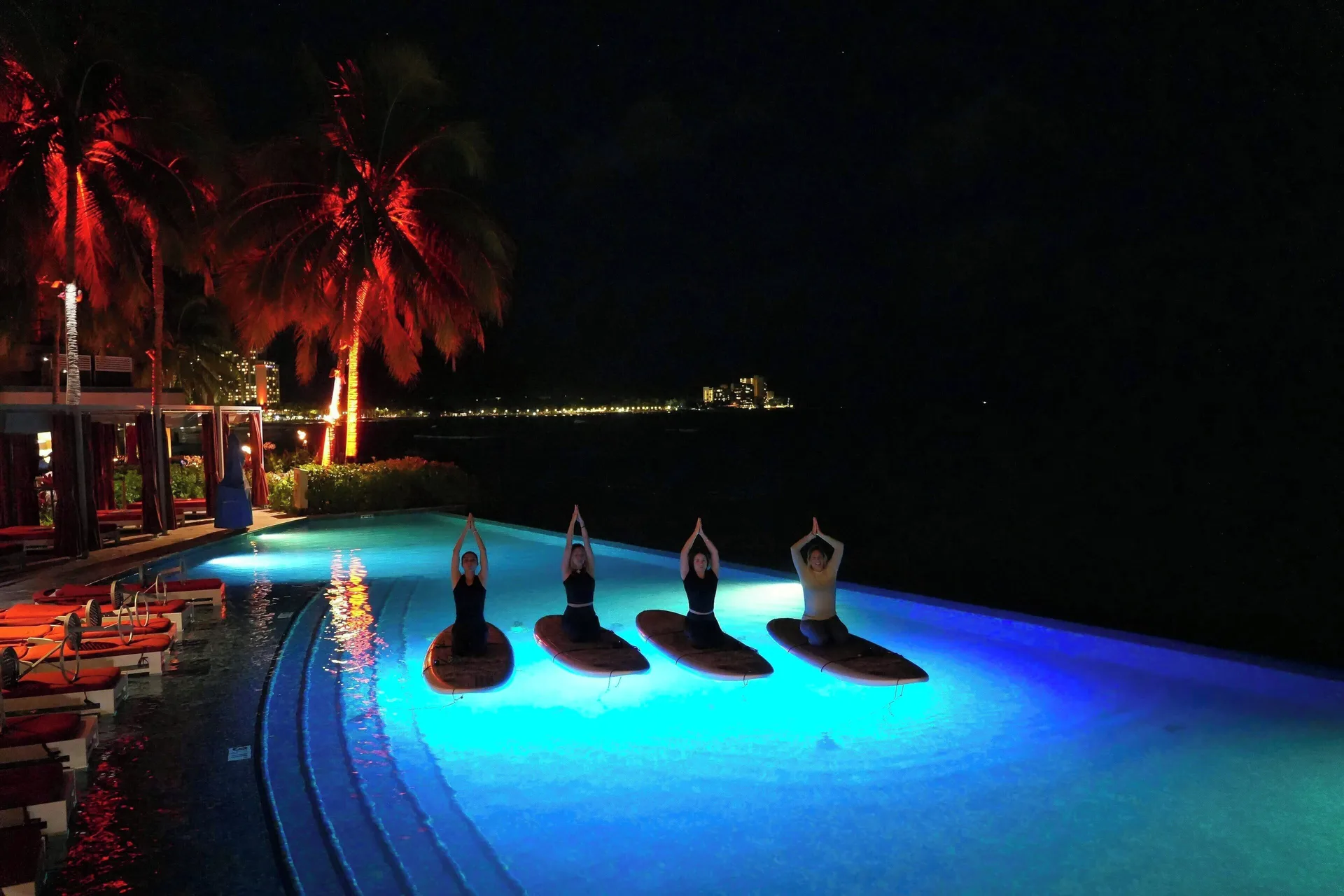 Night paddleboard yoga in a glowing pool at Sheraton Waikiki Beach Resort.